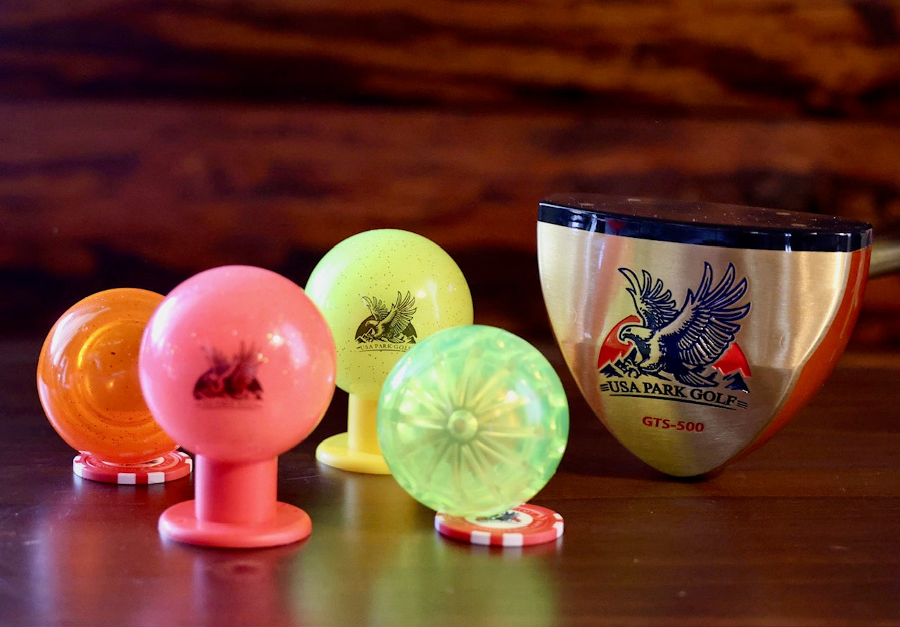 Colorful golf balls with a USA Park Golf brand park golf club on a wooden surface.